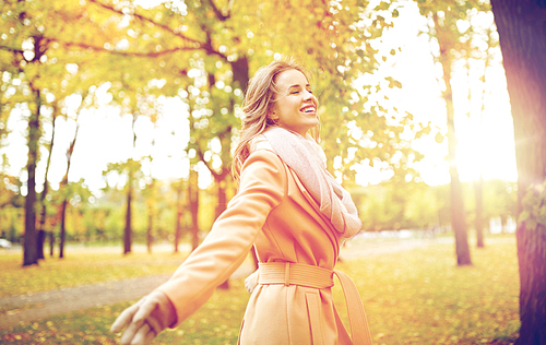 season and people concept - beautiful happy young woman walking in autumn park