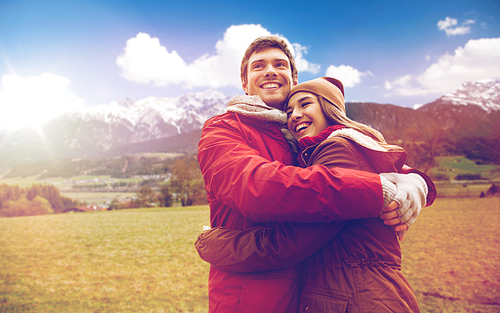 tourism, travel and people concept - happy young couple hugging over alps mountains background