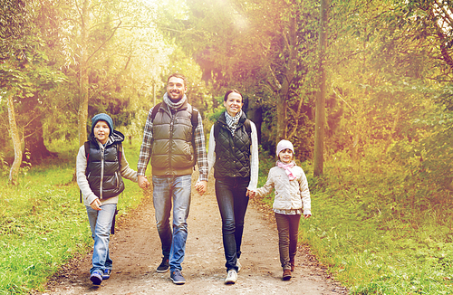 hike, travel, tourism and people concept - happy family walking with backpacks in woods