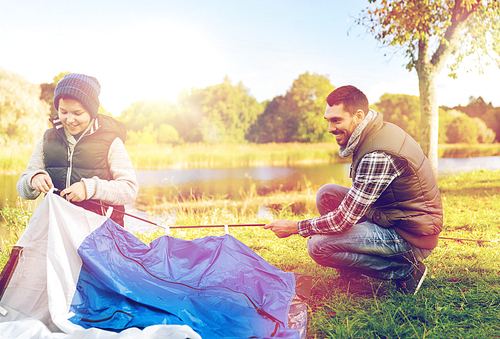 tourism, travel and hike concept - happy father and son hiking and setting up tent outdoors