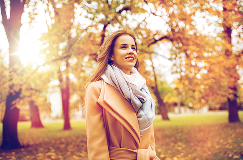 season and people concept - beautiful happy young woman walking in autumn park