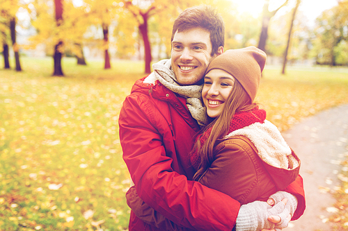 love, relationships, season and people concept - happy young couple hugging in autumn park