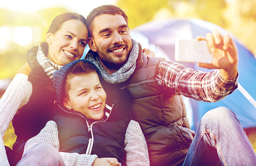 hike, technology and travel concept - happy family with smartphone taking selfie at campsite