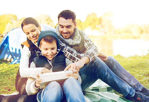 tourism, travel, hike and technology concept - happy family with tablet pc computer and tent at camp site