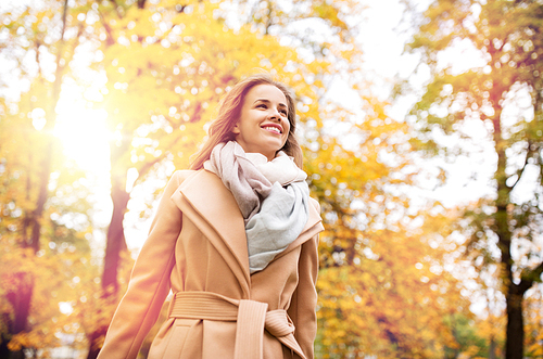 season and people concept - beautiful happy young woman walking in autumn park