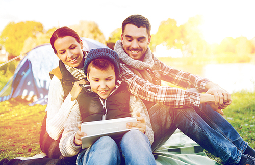 tourism, travel, hike and technology concept - happy family with tablet pc computer and tent at camp site