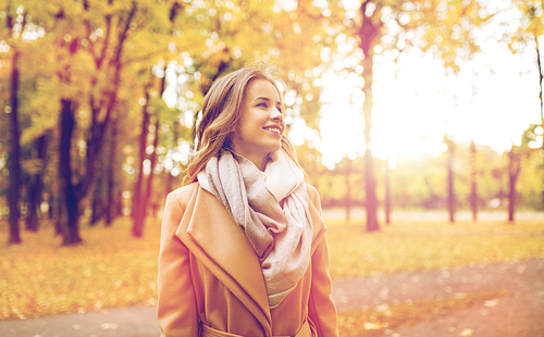 season and people concept - beautiful happy young woman walking in autumn park