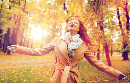 season and people concept - beautiful happy young woman walking in autumn park