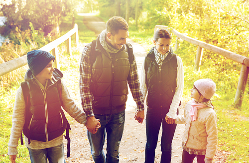 travel, tourism and hike people concept - happy family walking with backpacks outdoors