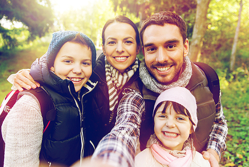 travel, tourism, hike and people concept - happy family with backpacks taking selfie and hiking