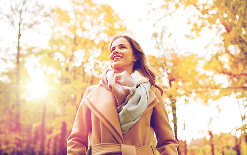 season and people concept - beautiful happy young woman walking in autumn park