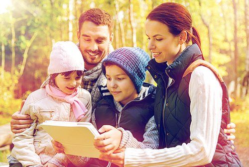 technology and people concept - happy family with tablet pc computer at camp in woods