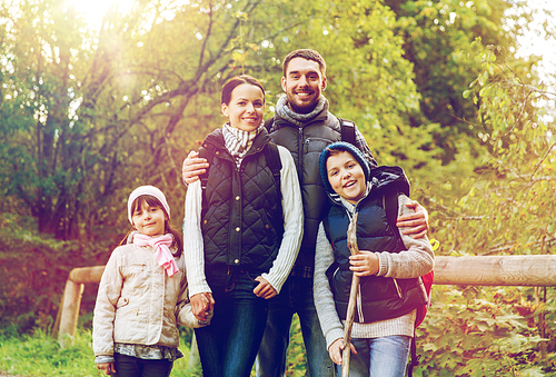 hike, travel, tourism and people concept - happy family walking with backpacks in woods