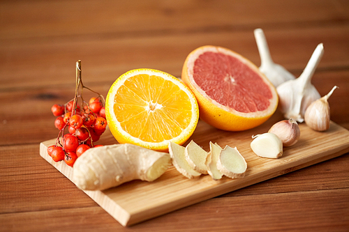 traditional medicine, cooking, food and ethnoscience concept - orange, grapefruit with ginger and garlic on wooden board