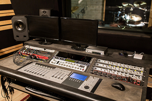music, technology, electronics and equipment concept - mixing console and computer monitors at sound recording studio