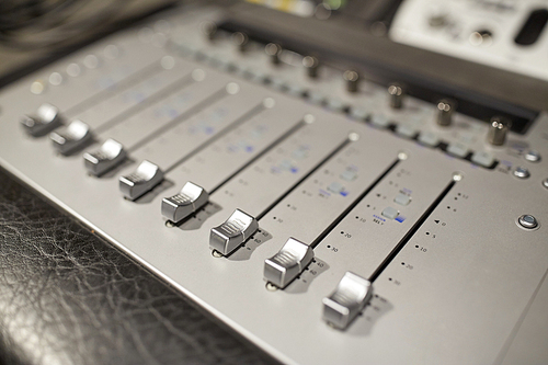 music, technology, electronics and equipment concept - mixing console at sound recording studio
