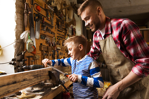 family, carpentry, woodwork and people concept - happy father and little son with rasp grinding wood plank at workshop