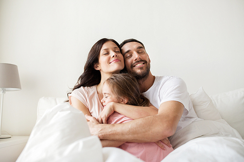 people, family and morning concept - happy child hugging parents in bed at home