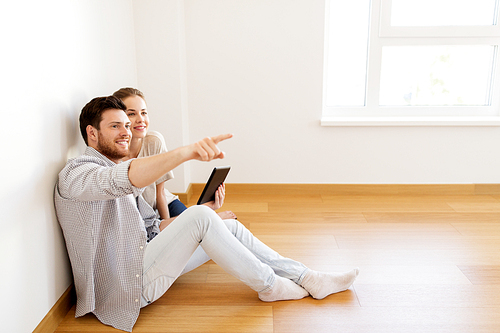 mortgage, people and real estate concept - happy couple with tablet pc computer at empty room of new home