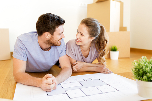 mortgage, people and real estate concept - happy couple with boxes and blueprint moving to new home