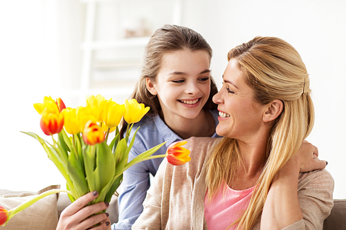 people, family and holidays concept - happy girl giving tulip flowers to her mother at home