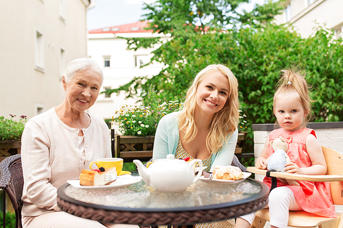 family, generation and people concept - happy smiling mother, grandmother and granddaughter at cafe or restaurant terrace