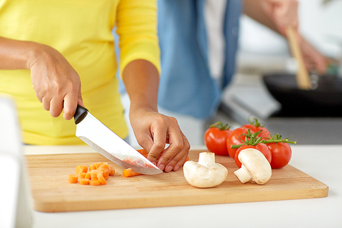 cooking, food and people concept - close up of african woman hands with knife chopping vegetables on cutting board