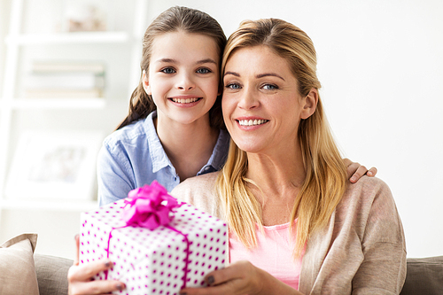 people, holidays and family concept - happy girl giving birthday present to mother at home