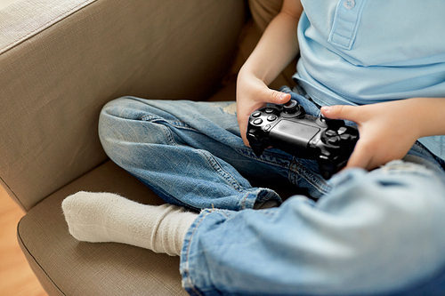 leisure, children, technology and people concept - close up of little boy with gamepad playing video game at home