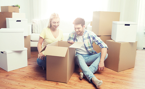 moving, people, repair and real estate concept - smiling couple looking into big cardboard box at new home