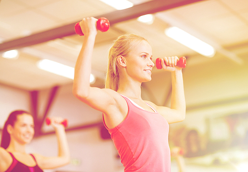 fitness, sport, training, gym and lifestyle concept - group of smiling people working out with dumbbells in the gym