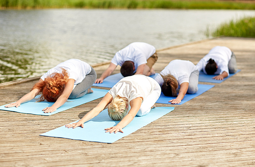 fitness, sport, yoga and healthy lifestyle concept - group of people making childs pose on river or lake berth