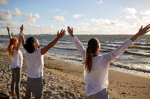 fitness, sport, yoga and healthy lifestyle concept - group of people meditating on beach