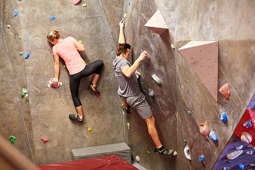 fitness, extreme sport, bouldering, people and healthy lifestyle concept - man and woman exercising at indoor climbing gym wall