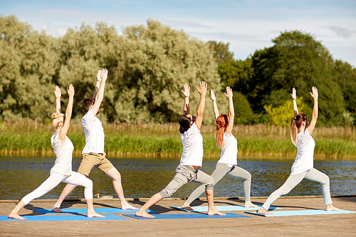 fitness, sport, yoga and healthy lifestyle concept - group of people making high lunge or crescent pose on river berth