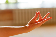 yoga, gesture and healthy lifestyle concept - hand of meditating yogi woman at studio showing gyan mudra