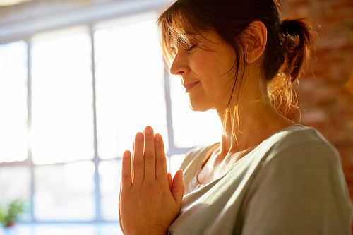 religion, faith, harmony and people concept - close up of yogi woman meditating at yoga studio