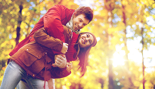 love, relationships, season and people concept - happy young couple having fun in autumn park