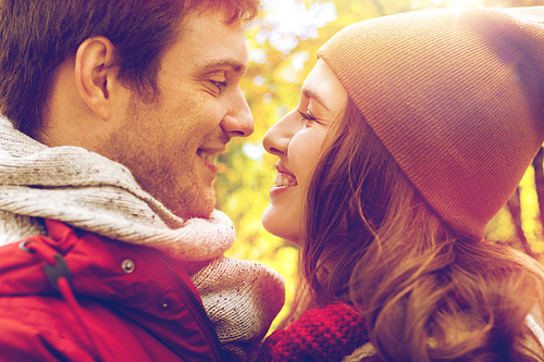 love, relationships, season and people concept - close up of happy young couple kissing outdoors