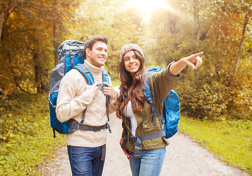 adventure, travel, tourism, hike and people concept - smiling couple with backpacks in autumn forest