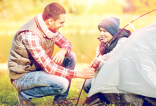 travel, tourism, hike and family concept - happy father and son setting up tent outdoors