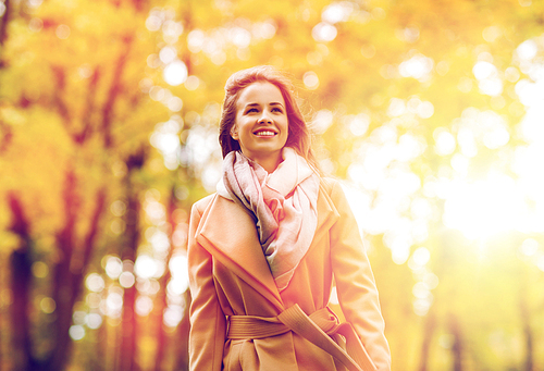 season and people concept - beautiful happy young woman walking in autumn park