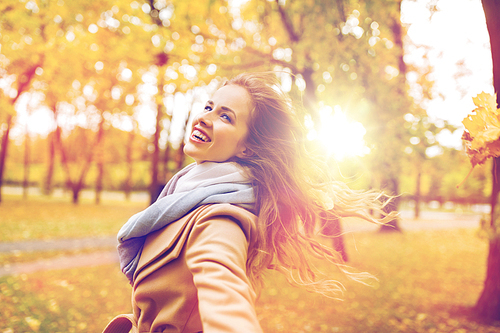 season and people concept - beautiful happy young woman walking in autumn park