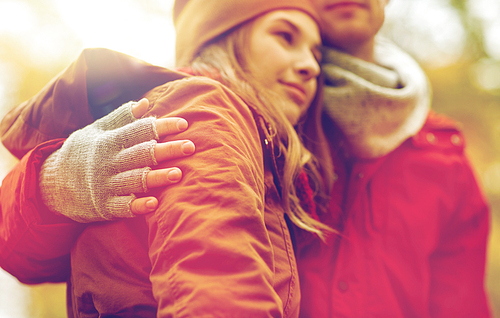 love, relationships, season and people concept - close up of happy young couple hugging in autumn park