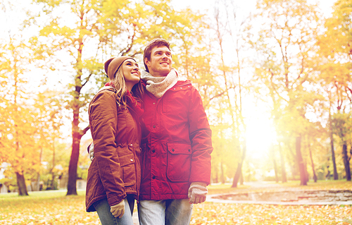 love, relationships, season and people concept - happy young couple walking in autumn park