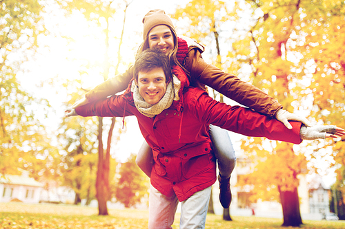 love, relationships, season and people concept - happy young couple having fun in autumn park