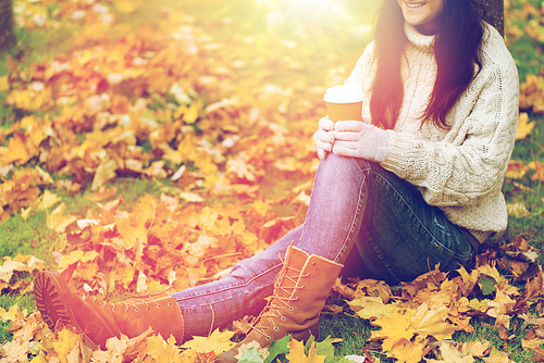 season, technology and people concept - close up of young woman drinking coffee from paper cup in autumn park