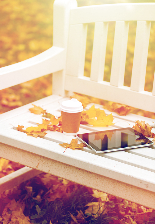 season, technology and advertisement concept - tablet pc computer and coffee paper cup on bench in autumn park