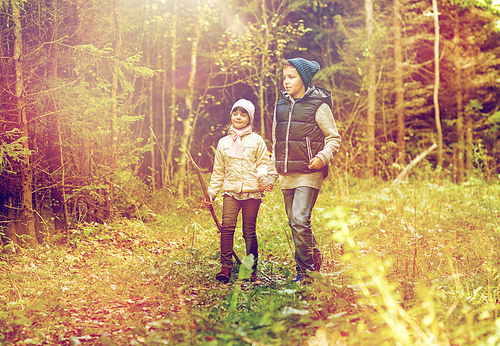 childhood, hiking, family, friendship and people concept - two happy kids walking along forest path