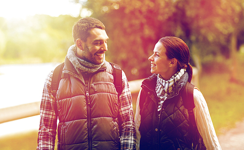 adventure, travel, tourism, hike and people concept - happy family couple walking with backpacks in woods